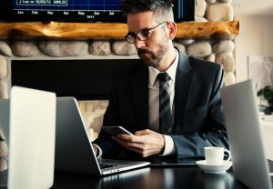 businessman in formal attire working on a laptop and smartphone paying international contractors